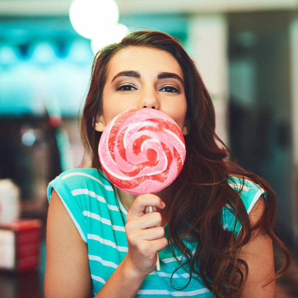 Im a candy kinda girl. Cropped portrait of an attractive young woman eating a giant lollipop in a retro diner - Foto, immagini