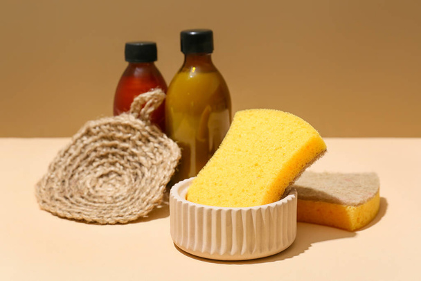 Household sponges and bottles on color background - Photo, image