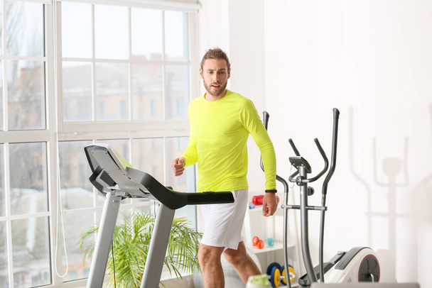 Sporty young man using step machine in gym - Fotó, kép