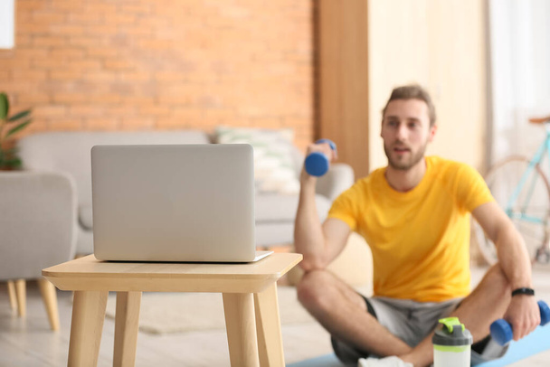 Спортивний молодий чоловік використовує ноутбук для онлайн-навчання вдома
 - Фото, зображення