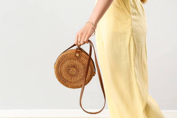 Elegant woman with stylish rattan handbag on light background, closeup - 写真・画像