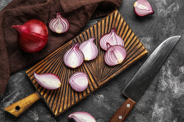 Composition with wooden board of cut red onion and knife on dark background - Foto, Imagem
