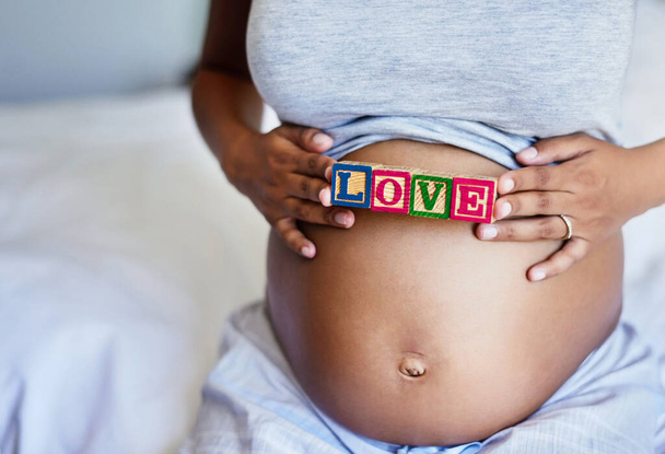 My love grows for you everyday. a pregnant woman with wooden blocks on her belly that spell the word love - Fotoğraf, Görsel