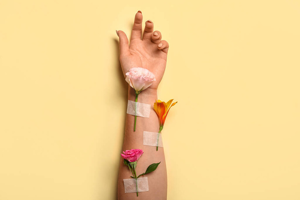Woman with beautiful flowers and adhesive tape on beige background - Photo, image