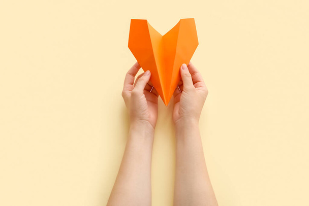 Женщина с плоскостью из оранжевой бумаги на бежевом фоне - Фото, изображение