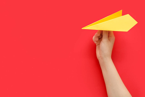Woman with yellow paper plane on red background - Foto, afbeelding