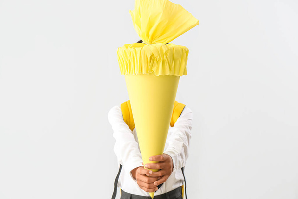 Little boy with yellow school cone on light background - Foto, Imagen