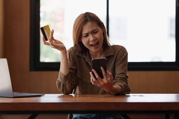 Μια αγχωμένη γυναίκα κατά τον έλεγχο του λογαριασμού της πιστωτικής κάρτας στην εφαρμογή smartphone. Έννοια ηλεκτρονικής πληρωμής - Φωτογραφία, εικόνα