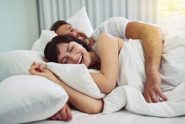Ми повинні залишитися в ліжку трохи довше. розслаблена молода пара намагається спати один в одного руки в ліжку в ранкові години
 - Фото, зображення