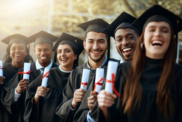 Success belongs to us. Portrait of a group of young students holding their diplomas on graduation day - 写真・画像