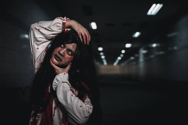 Happy halloween day concept. Screaming zombie female face with blood grabs her head to twist it off, Horror bloodthirsty woman ghost or zombie she is horror scary with breaks her neck at dark night - Fotoğraf, Görsel