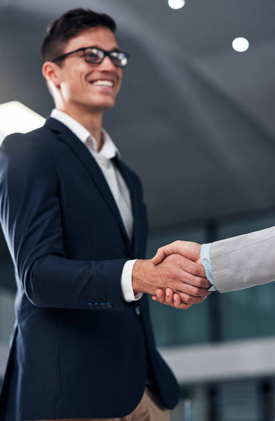 Trust plays a big role in business. two businessmen shaking hands in a modern office - Photo, image