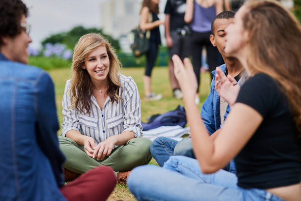 Спілкування про життя. група молодих студентів, які навчаються разом, сидячи в парку на вулиці протягом дня
 - Фото, зображення