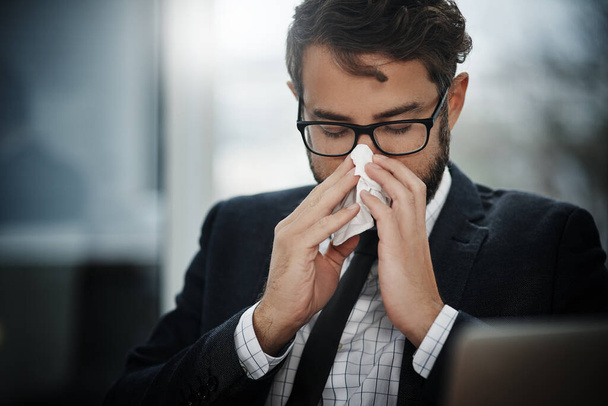 I cant deal with getting sick right now. a young businessman blowing his nose in an office - Valokuva, kuva