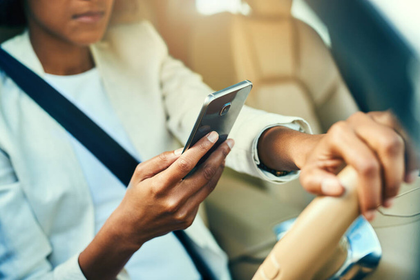 Looks like Im in for a surprise in the office. an unrecognizable businesswoman browsing on her mobile phone while driving in a car during the day - Foto, imagen