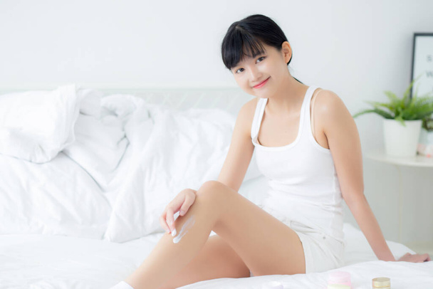 Krásná mladá asijská žena nanášení krém nebo krém na nohy s hydratační krém s cartridge na posteli, krása asijské dívka nanášení péče o pleť dotek nohy s kosmetickým make-up, péče o pleť koncept. - Fotografie, Obrázek