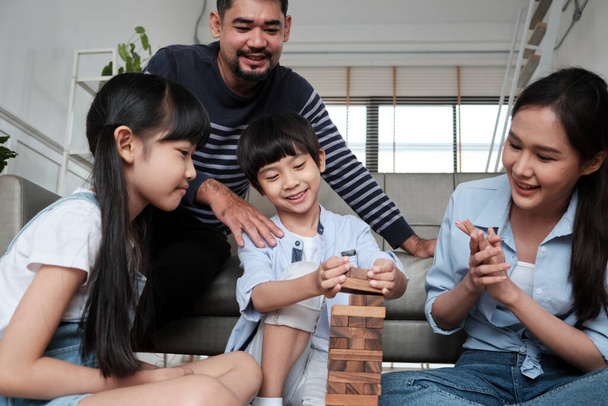 Happy Asian lovely Thai family activity, parents, dad, mum, and children have fun playing and joyful wooden toy blocks together on living room floor, leisure weekend, and domestic wellbeing lifestyle. - Zdjęcie, obraz