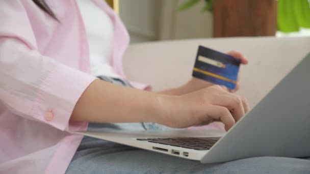 Handen van de vrouw zitten op de bank met behulp van laptop computer online winkelen met creditcard kopen op internet, geluk meisje betaling met e-business op de bank, aankoop en betaling, business concept. - Video