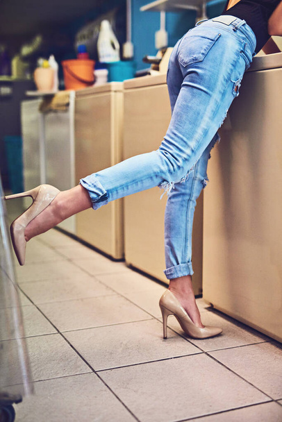 Everything she does she does in style. an unrecognizable womans bottom half showing her wearing high heels while doing her washing in a laundry room - Foto, Imagem