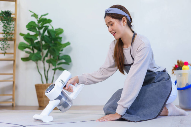 Концепція домогосподарства, Housemaid тримає пилосос для пилососа і чищення килима на підлозі
. - Фото, зображення