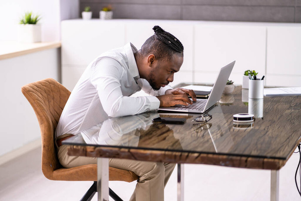 African Man Bad Posture Working Typing At Desk - 写真・画像