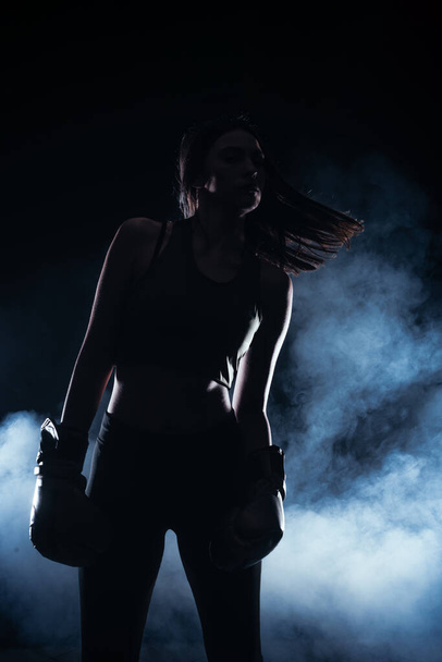 ボクシンググローブを持つ女性モデルの背景に白い煙とシルエットの肖像画 - 写真・画像