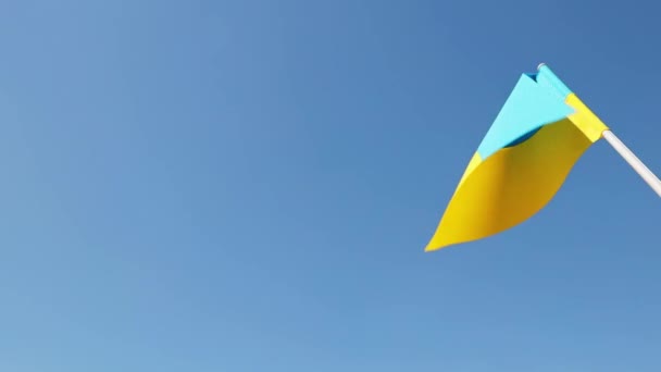 Ukraine national flag in human hand waving by wind in front of clear blue sky. Small blue-yellow symbol souvenir of nation, freedom, nationality, strength, will and honor. High quality FullHD footage - Video, Çekim