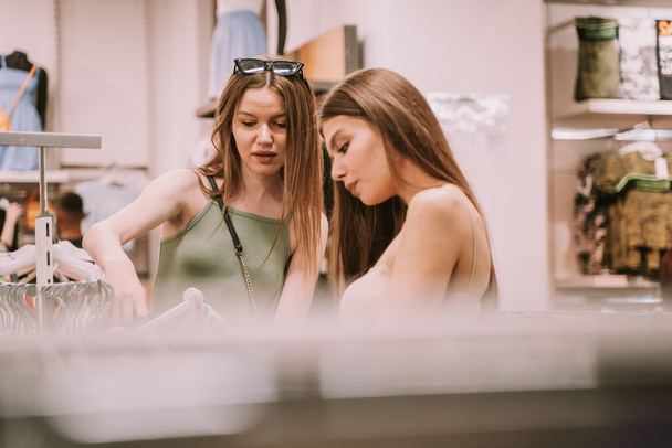 Beautiful girls trying to find something good looking in the store at the mall - 写真・画像