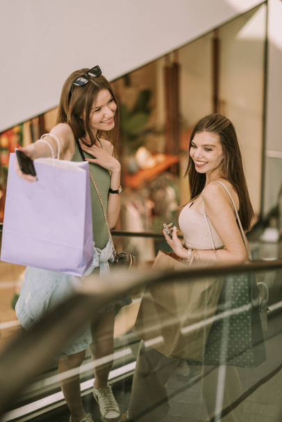 Close up of two pretty girls going up on the escalator at the mall - Foto, Imagen