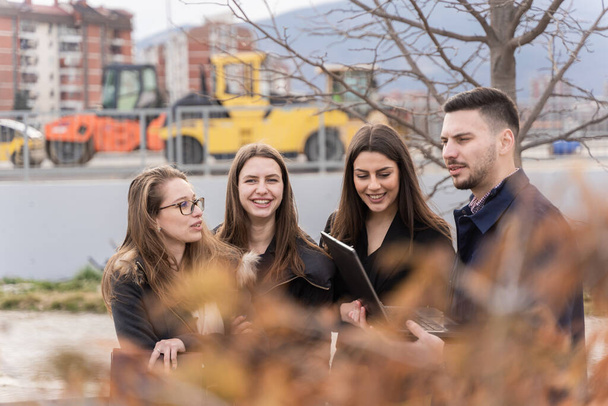 Група молодих бізнесменів дивляться на вершину коліна і обговорюють ідеї та плани свого бізнесу, посміхаючись
 - Фото, зображення