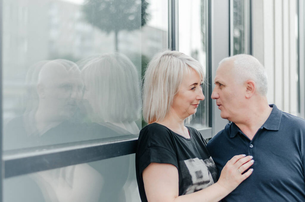 a man and a woman are hugging near a window in the city - Photo, Image
