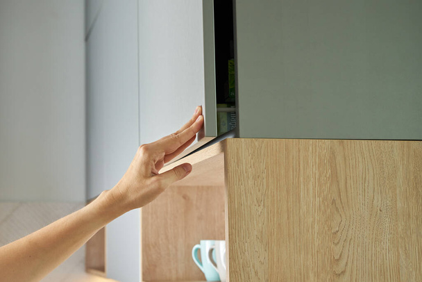 Female hand open kitchen cabinet, Cupboard door in kitchen furniture - Фото, изображение