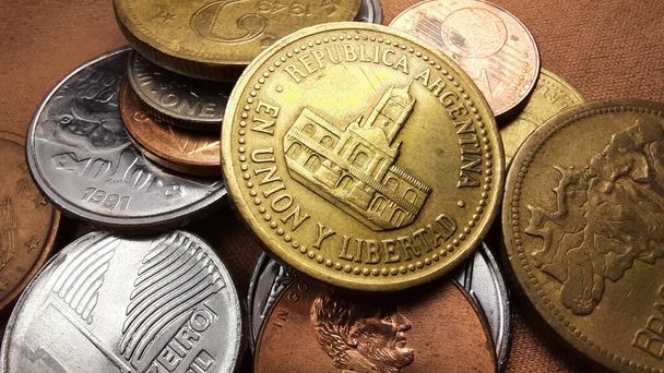 Золота монета Песо, з зображенням будівлі Кабільдо в Буенос-Айресі, разом з колекцією різних старих монет на коричневому тлі.. - Фото, зображення