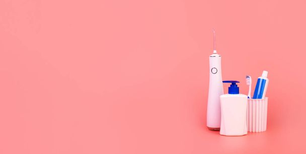 composition with manual toothbrush, irrigatoro, toothpaste,  oral hygiene products and soap on colored background. oral care concept. hygiene concept - Фото, изображение