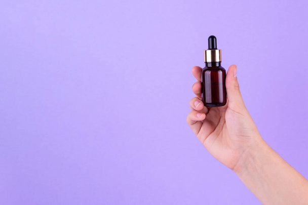 Serum bottle in female hands, top view. Transparent moisturizer for skin care. Nourishing essential oil in glass bottle with pipette. Liquid emulsion with hyaluronic acid. Beauty cosmetic spa product - Photo, Image