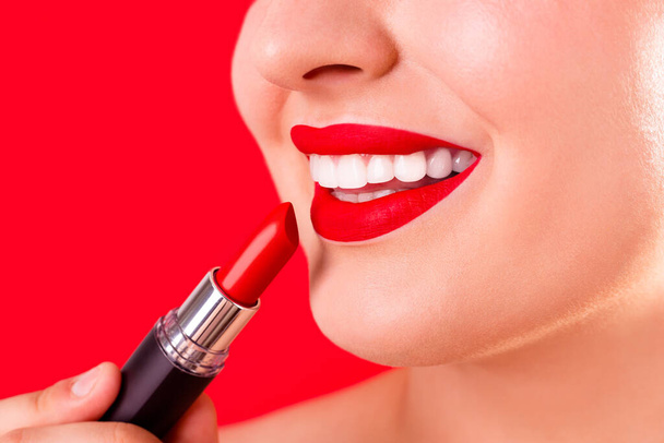 Healthy white smile close up. Beauty woman with perfect smile, lips and white teeth. Beautiful Model Girl with red lips applying red lipstick. Teeth whitening and cleaning, dental care. - Foto, Bild