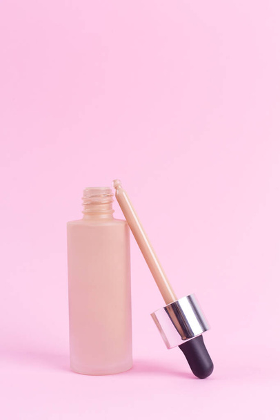 Opened liquid foundation cream with pipette unbranded bottle on a pink background. BB cream for professional make-up, eyedropper for applying to the face. Cosmetic female accessory, fluid. Mock up - Foto, Imagen
