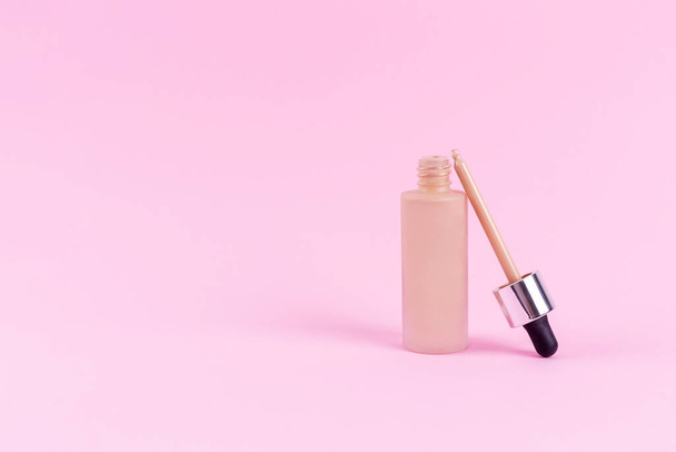 Opened liquid foundation cream with pipette unbranded bottle on a pink background. BB cream for professional make-up, eyedropper for applying to the face. Cosmetic female accessory, fluid. Mock up - Fotoğraf, Görsel