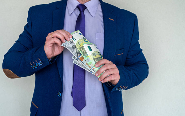 Деловой человек в костюме держит банкноту евро и доллара для обменного курса. Финансовая концепция. - Фото, изображение