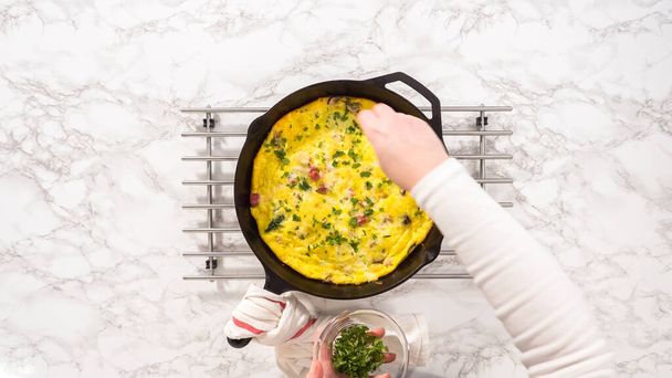 Flat lay. Step by step. Freshly baked spinach and ham frittata in cast iron skillet. - Foto, Imagen