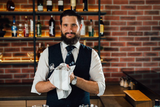 caucasian barman cleaning glasses in cafe - Fotó, kép