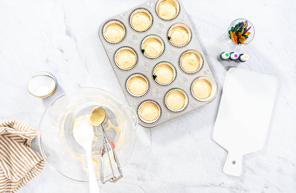 Flat lay. Vanilla cupcake batter in foil cupcake liners to bake Mardi Gras vanilla cupcakes. - Photo, Image