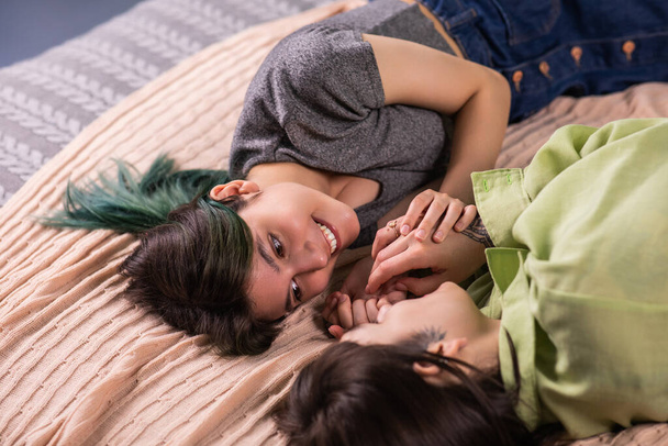 Very attractive two young ladies best friends laying down on the bed discussing with each other touching slowly hands concept of LGBT a freedom equality friendship. Portrait - Foto, Imagen