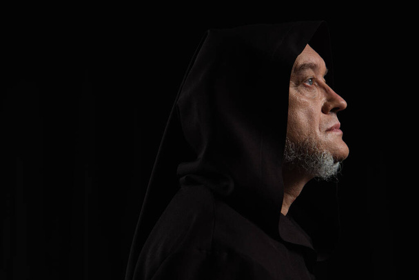 Profil des geheimnisvollen Mönchs mit dunkler Kapuze isoliert auf schwarz - Foto, Bild