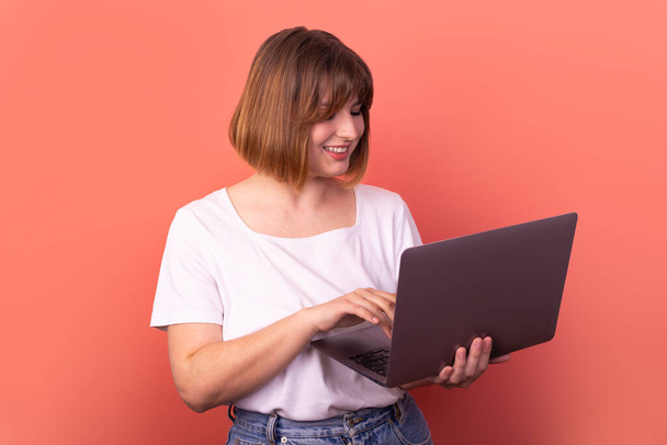 Portret van aantrekkelijke verbaasd vrolijke meisje agent makelaar met behulp van laptop plezier geïsoleerd over roze pastel kleur achtergrond - Foto, afbeelding