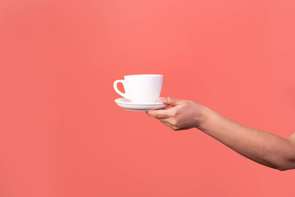 γυναίκα χέρι κρατώντας ένα φλιτζάνι καφέ απομονώνονται σε ροζ παστέλ φόντο. μακιγιάρισμα - Φωτογραφία, εικόνα