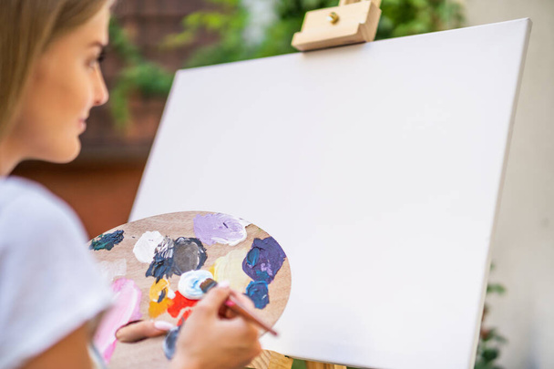 Woman enjoys painting on canvas outdoor. - Фото, зображення