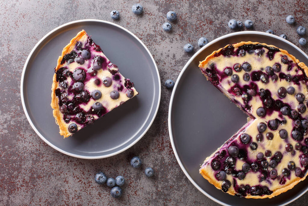 Homemade fresh blueberry tart with custard close-up in a plate on the table. Horizontal top view from abov - Fotó, kép