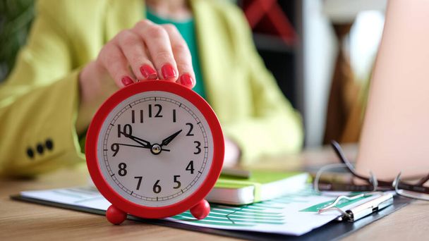 Close-up of woman putting red alarm clock on desk, time management and deadline. Female boss at workplace in office - Foto, Imagem