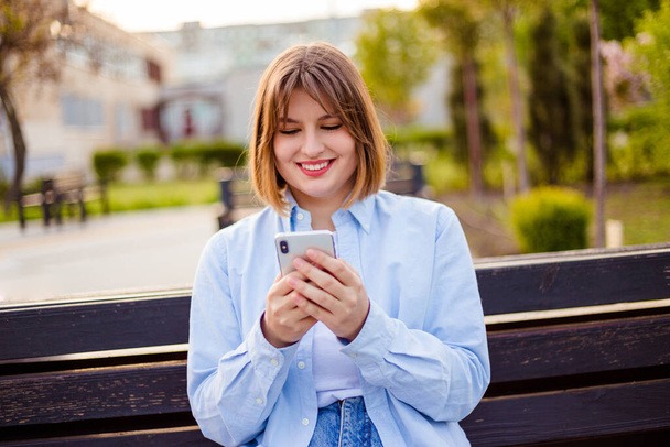 Photo of charming pretty young lady communicating modern gadget sitting bench smiling outside urban city street - Foto, Bild